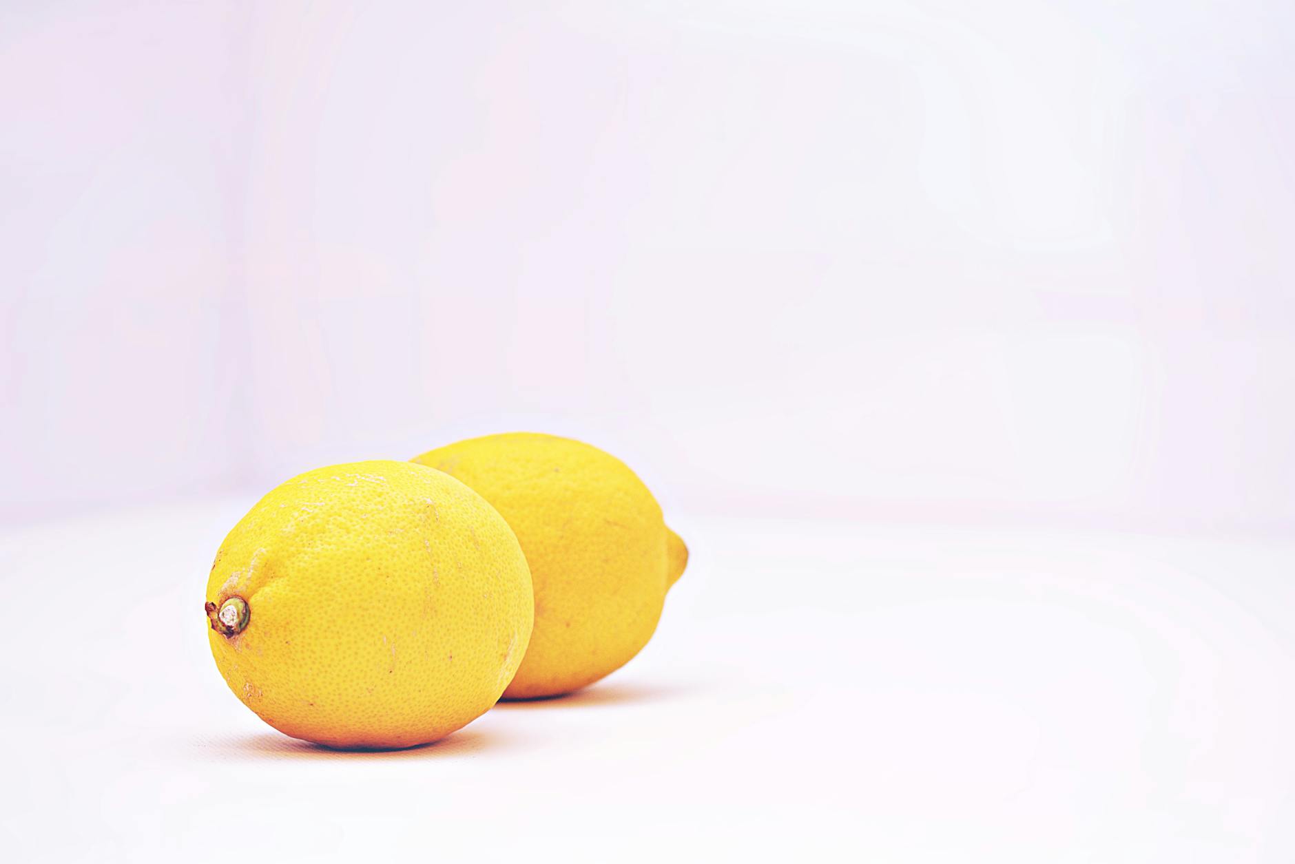 A blue silicone lemon clitoral vibrator held in hand against a purple background