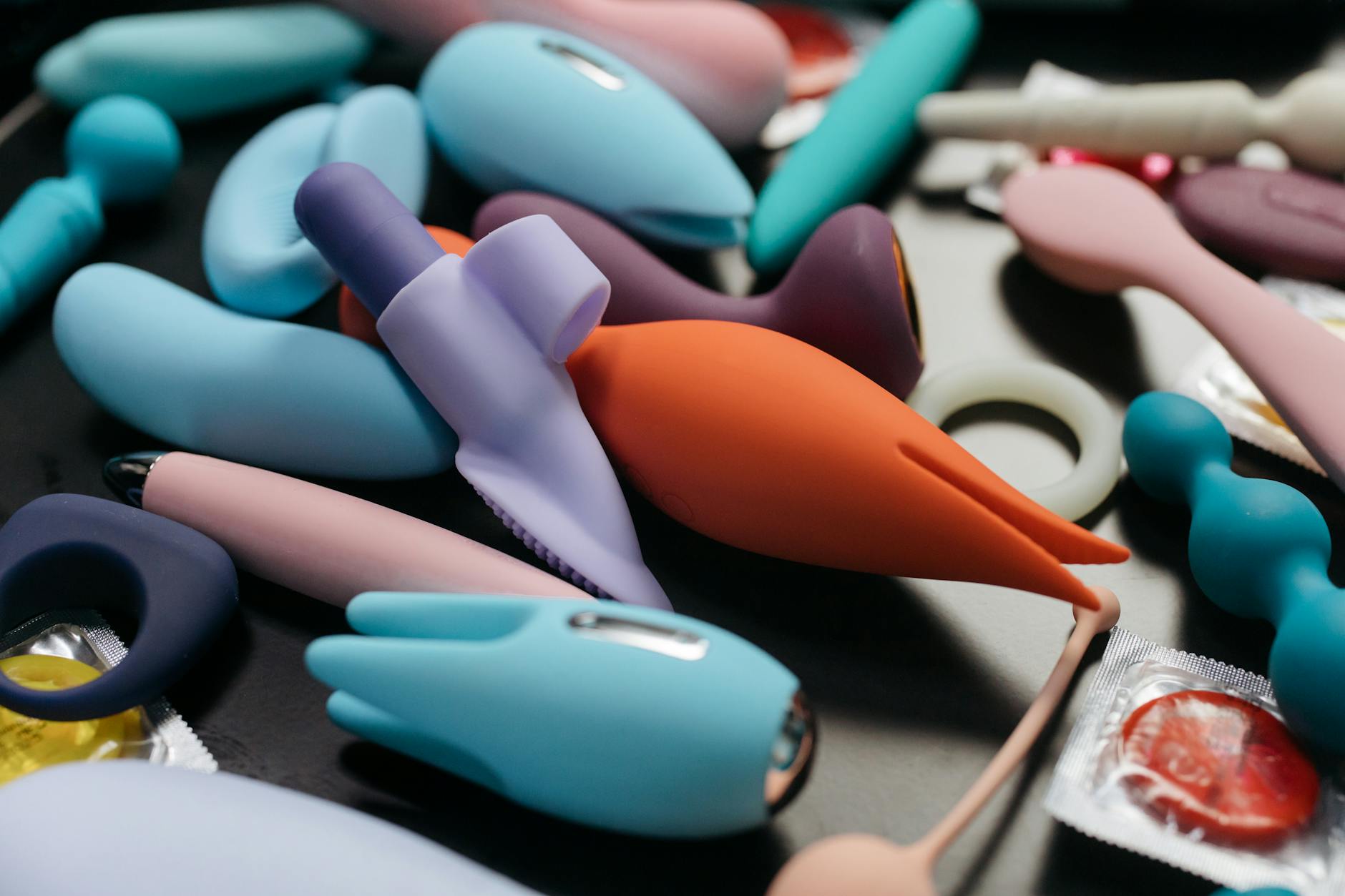 Une main atteignant une collection de jouets de plaisir colorés sur une table, symbole de l'exploration sexuelle en couple