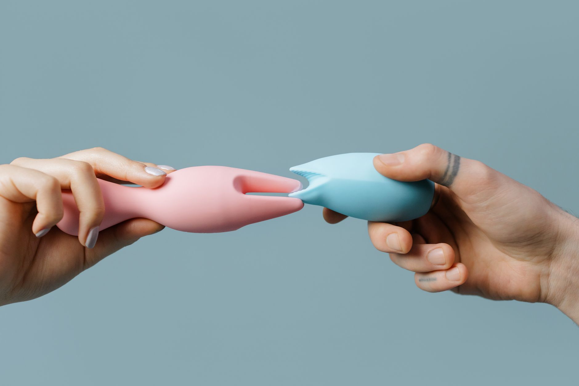 Main tenant un vibromasseur clitoridien bleu sur fond violet, illustrant l'autonomie du plaisir féminin