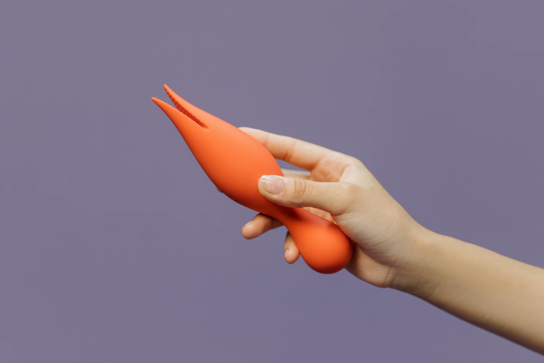 Gros plan d'une main tenant un vibromasseur citron contre un fond minimaliste, mettant en avant la sensualité moderne