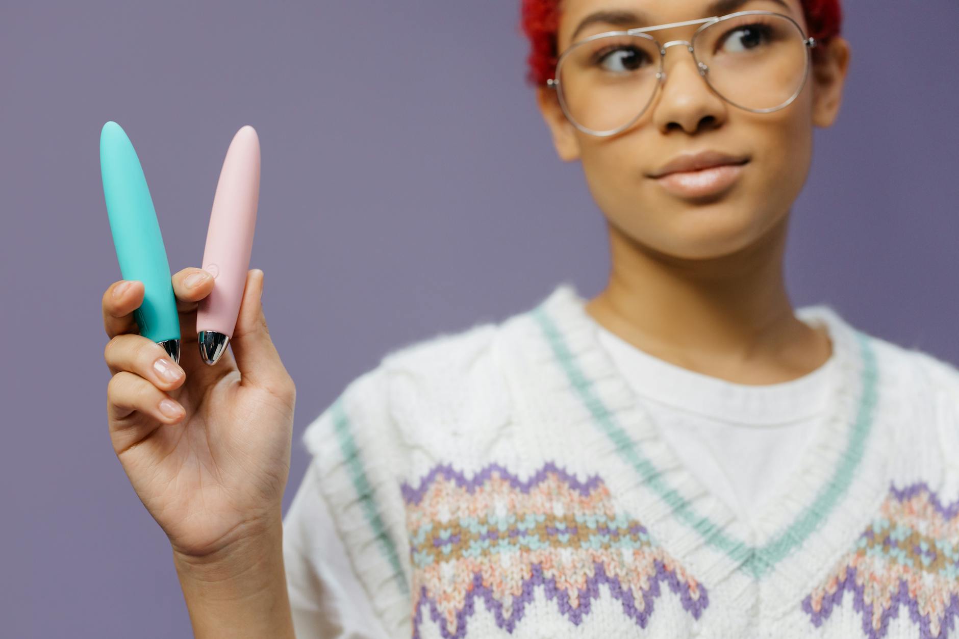 A woman holding two pastel clitoral vibrators, demonstrating solo pleasure options for couples exploration