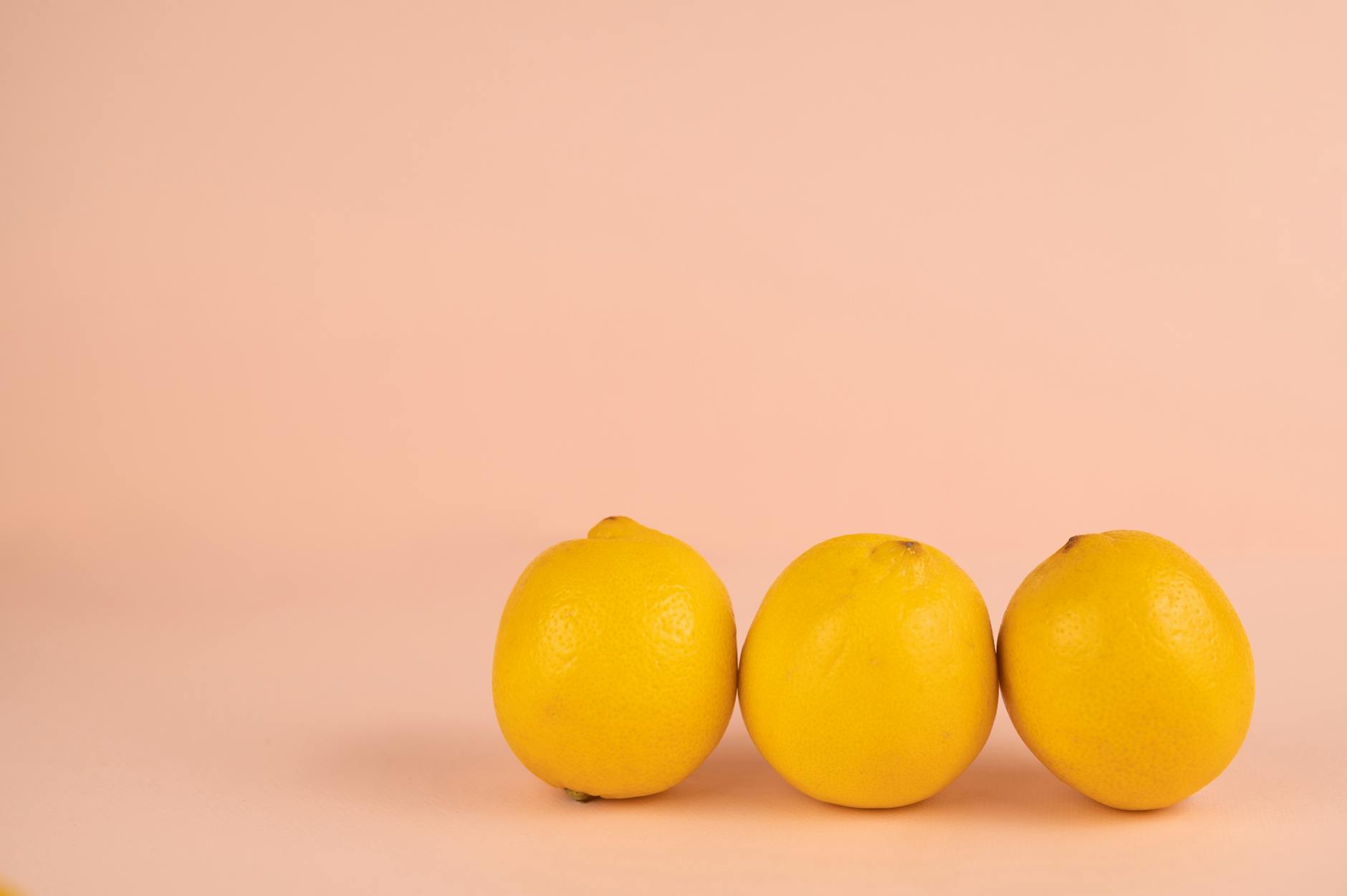 Citrons frais mûrs avec pelures éclatantes disposés sur fond pastel, représentant la vitalité et le renouvellement du plaisir